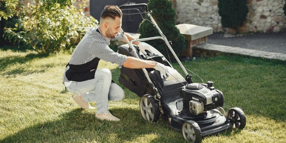 man cleaning a lawn mower